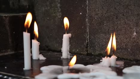 Vista-Cercana-De-Muchas-Velas-Encendidas-En-El-Suelo