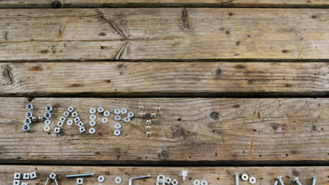 happy fathers day text with old nails, screws, nuts and bolts arranged on wooden plank