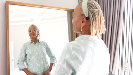 Mujer-Mayor-Afroamericana-Mirando-El-Espejo,-Vistiendo-Camisa-Azul-Claro