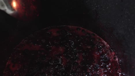 una olla con bayas hirviendo para hacer mermelada, revolviendo con una cuchara grande a cámara lenta