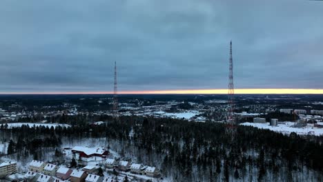 drone orbiting radio towers on a hill, dark, winter evening in lahti, finland