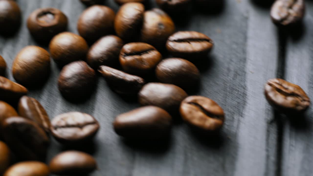 Coffee grain. Brown roasted coffee beans scattered on wooden surface. Natural seeds of coffee. Macro shot.