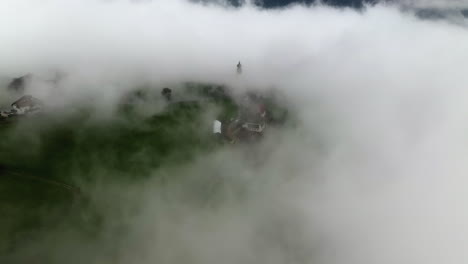 vista aérea a través de la espesa niebla, revelando la iglesia de san nicolás y la ciudad de renón, en italia