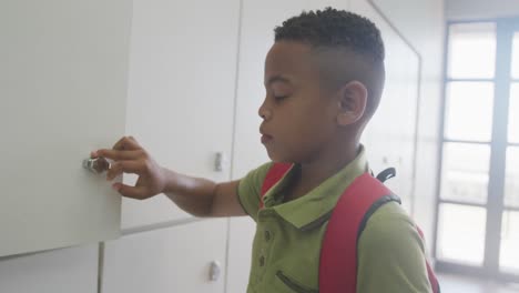 Video-of-african-american-boy-closing-locker-and-smiling-at-school