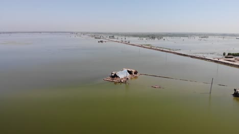 en pakistán, un dron captura una toma aérea de una casa desolada y dañada y el campo a su alrededor que ha sido sumergido por el agua