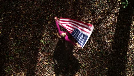 looking straight down as a woman spins and whips an american flag around in a forest