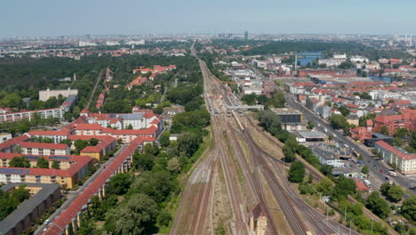 Imágenes-Inclinadas-Hacia-Abajo-De-La-Línea-Ferroviaria-Recta-Que-Atraviesa-El-Vecindario-Urbano.-Vista-Aérea-Del-Tráfico-En-La-Vía,-Pasando-Trenes.-Berlín,-Alemania