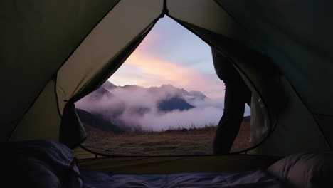 view from inside a tent of mountainous landscape with clouds at sunrise or sunset