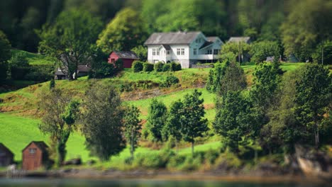 a neat cottage with a barn nearby on the lush hills on the coast of hardanger fjord