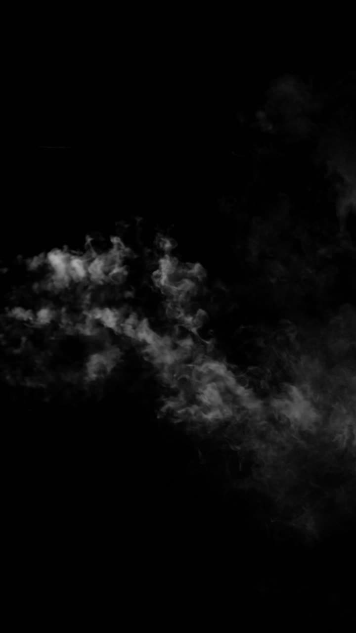 A dense cloud of realistic smoke drifts horizontally across a black background. A versatile vertical overlay element for compositing and special effects
