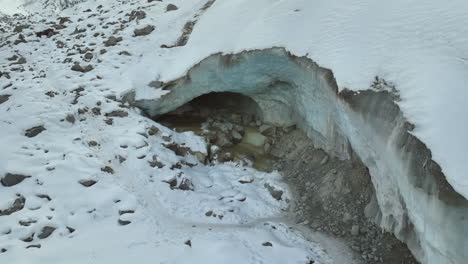 Slowly-drone-lowering-shot-of-melting-water-from-a-frozen-glacier