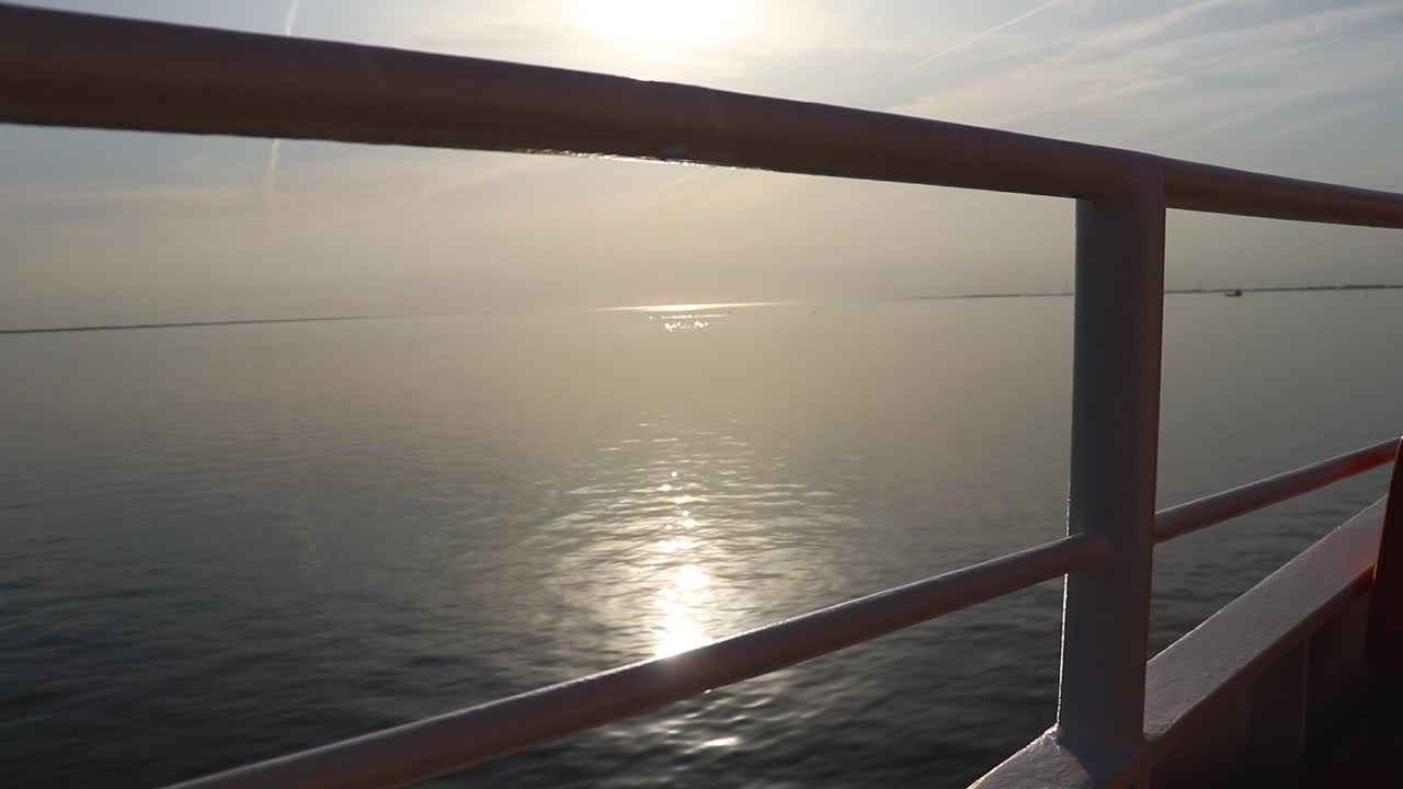 Sonnenaufgang auf der Fähre am Meer mit einem warmen, orangefarbenen Himmel.