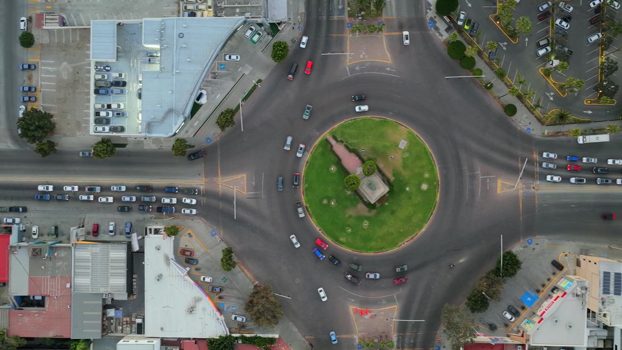 Independence Boulevard and Monumento México roundabout in the Paseo de los Héroes district of downtown Tijuana, Baja California, Mexico at rush hour traffic. Pan right top down aerial