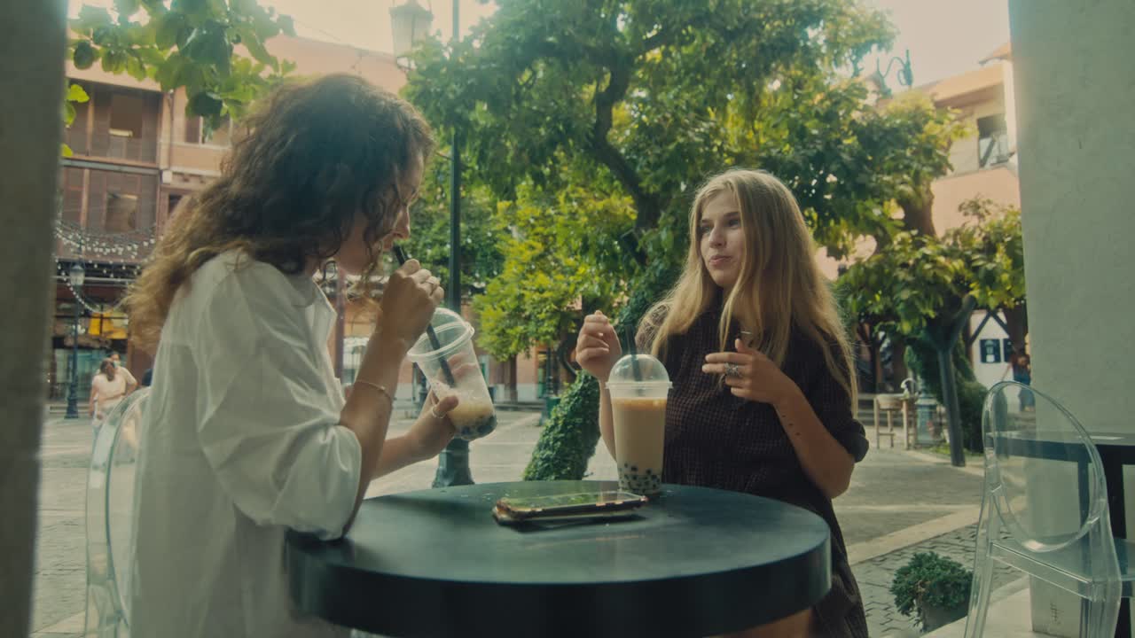 Two Friends Enjoying Bubble Tea at an Outdoor Cafe