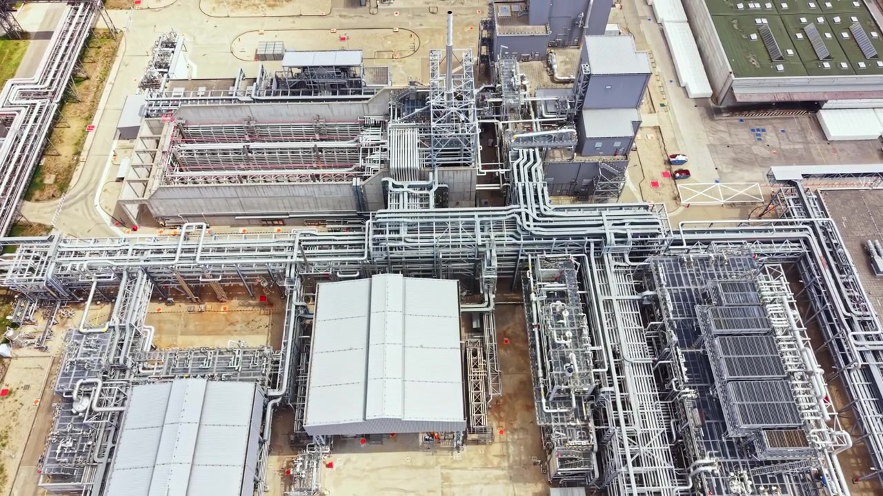 Sito industriale con tubi e strutture in una zona trafficata.