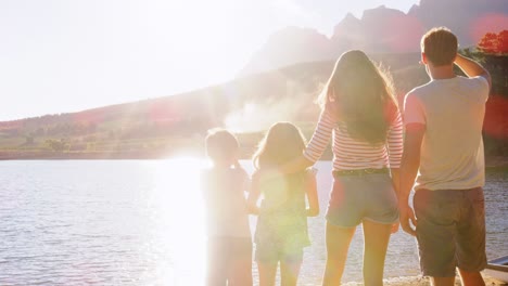 parents and two kids standing on jetty by lake, back view