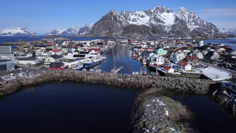 Fishing-boat-arriving-in-Norwegian-fishing-village-Henningsvaer-on-a-sunny-day-during-winter,-Lofoten,-Norway