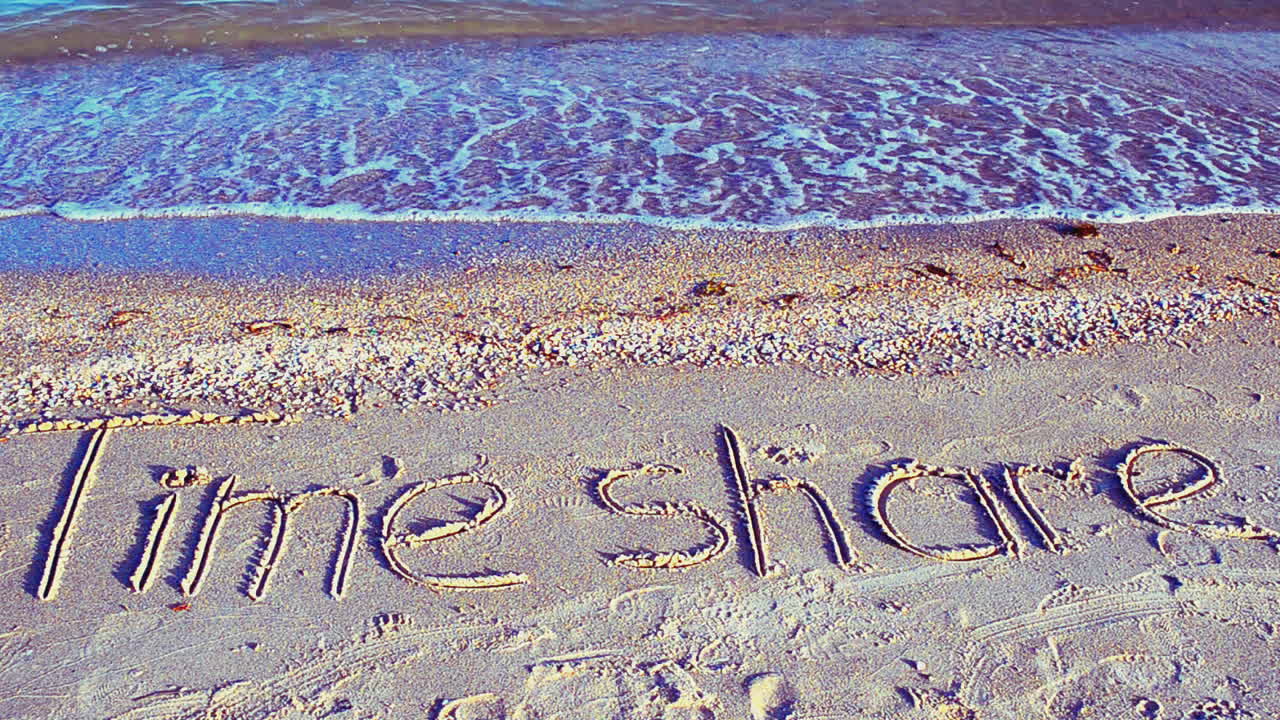Indskriften 'timeshare' i sandet på stranden. Optagelse på stranden