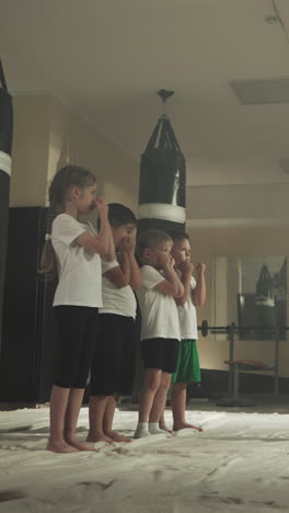 los niños hacen bloques con el entrenador en la escuela de artes marciales. los pequeños estudiantes de boxeo aprenden autodefensa bajo el control del instructor en el gimnasio en cámara lenta