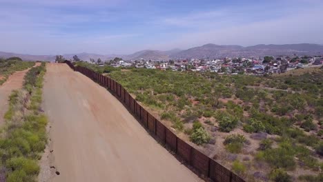 slow rising aerial along the us mexican border wall fence reveals the town of tecate mexico