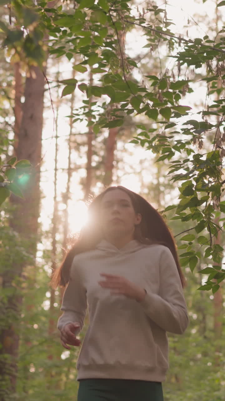 corredora femenina corriendo a través del bosque al amanecer. mujer joven disfruta de la actividad cardio rodeada de árboles densos. rutina matutina activa para dar forma al cuerpo