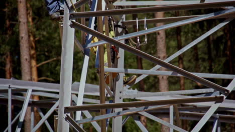 worker climbing metal towerstructure in forested area using harness
