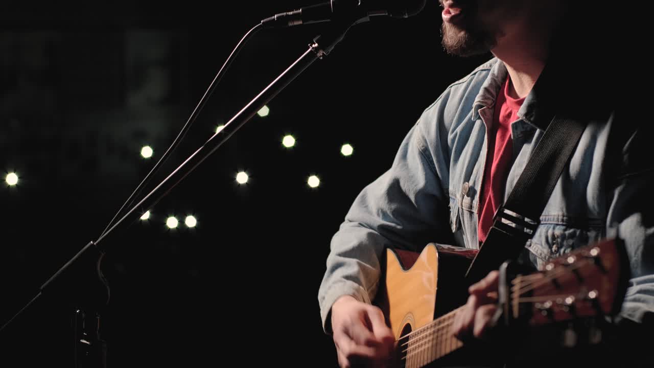 한 뮤지션이 큰 무대에서 기타를 연주하고 있으며, 관객들은 배경에 불을 들고 있습니다. 관객실은 아름다운 박이는 불빛으로 가득 차 있습니다.