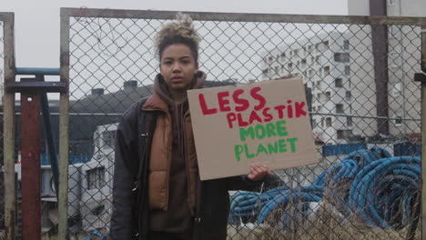 Junge-Amerikanische-Aktivistin,-Die-Während-Eines-Protestes-Gegen-Den-Klimawandel-Ein-Plakat-Aus-Pappe-Gegen-Die-Verwendung-Von-Kunststoffen-Hält,-Während-Sie-In-Die-Kamera-Schaut