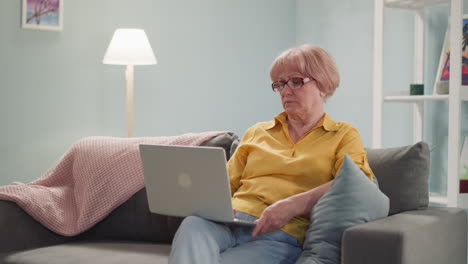 tired elderly woman in glasses for nearsighted sits on sofa