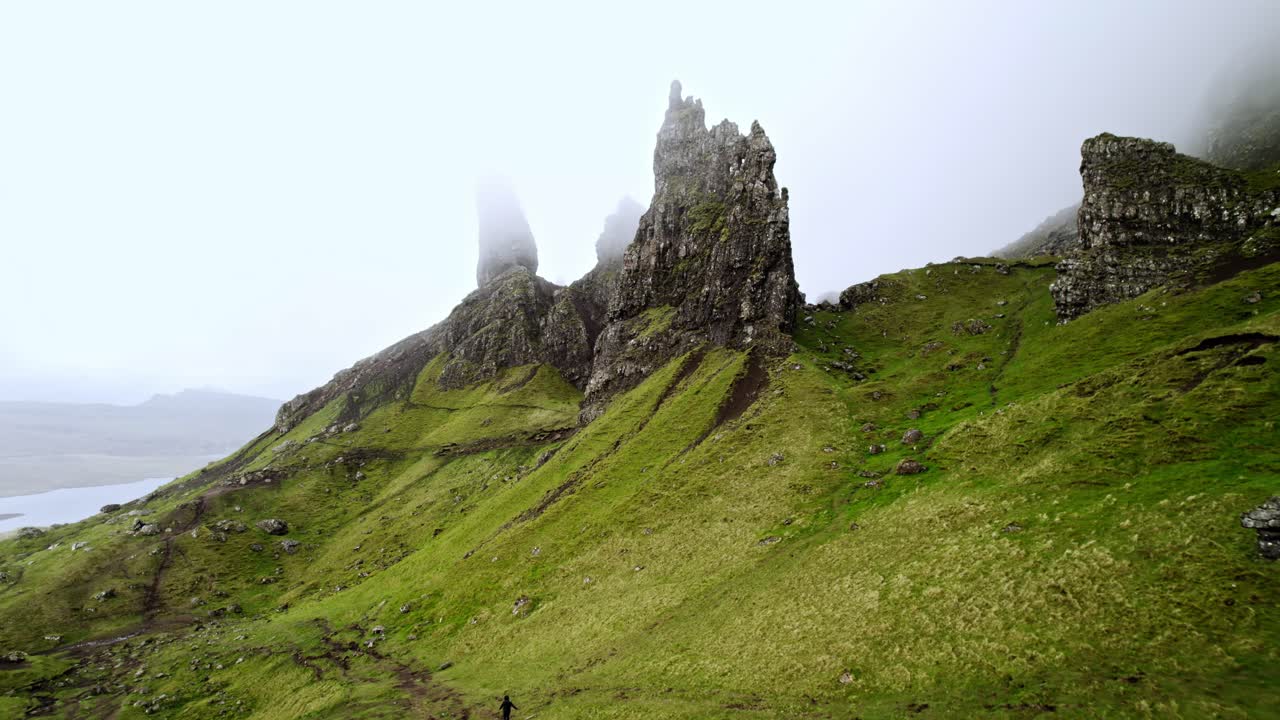짙은 안개가 스코틀랜드 스토르의 노인을 통과할 때 고독한 등산객이 길을 걸어갑니다.