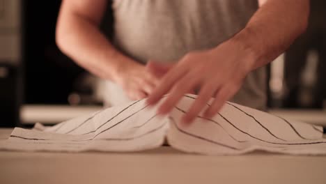 Man-covering-bread-dough-with-stripped-kitchen-cloth-before-letting-it-rise