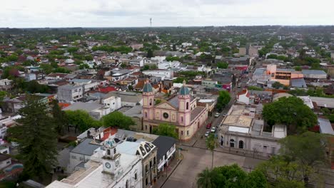 Sinking-aerial-of-small-town-and-flat-green-landscape-in-Argentina