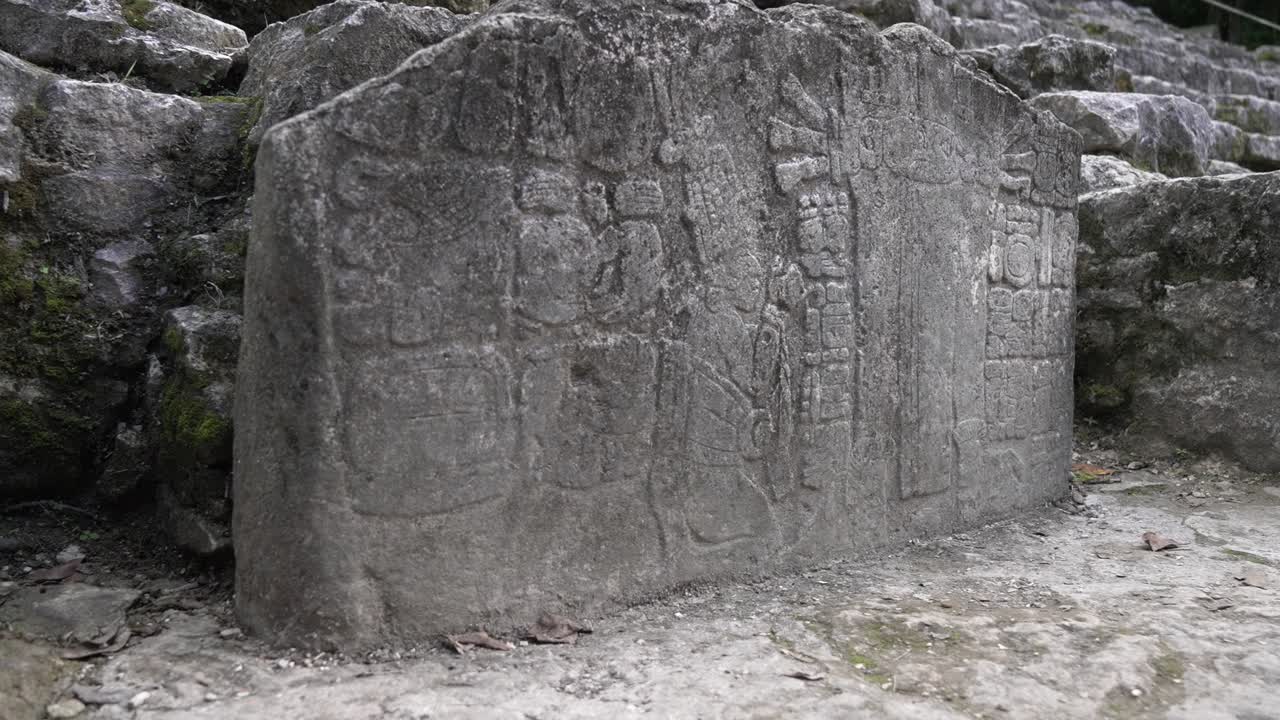 Dolly with focus change on detailed carvings on a stone slab with ancient Mayan artistry and symbols, figures and hieroglyphs in Yucatan, Mexico.