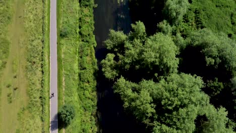 Die-Fluss-Stour-Drohnenaufnahmen-Mit-Einem-Typen,-Der-Nebenher-Fahrrad-Fährt