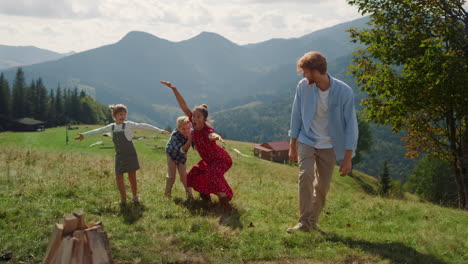 lächelnde familie spielt, zeigt lustige posen auf green hill. paar genießt spiele.