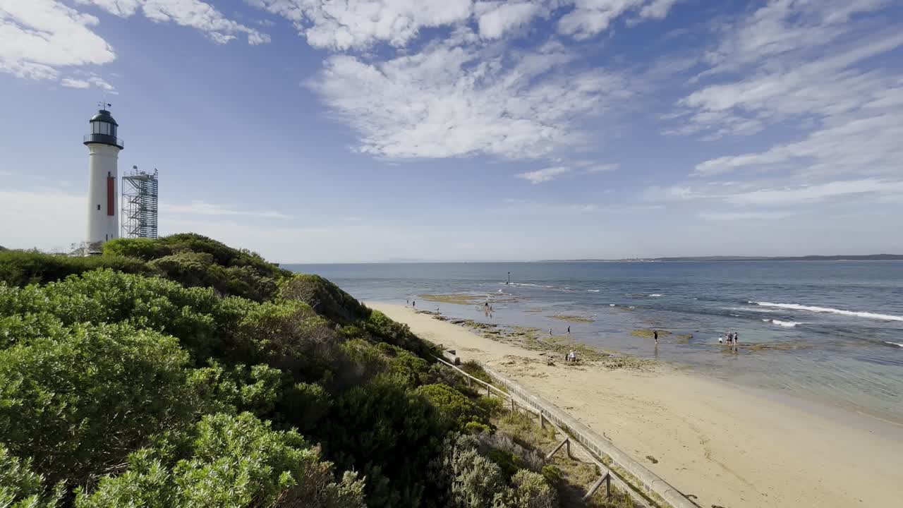 Queenscliff Lighthouse Overlooking A Beach With People During Summer On The Bellarine Peninsula.