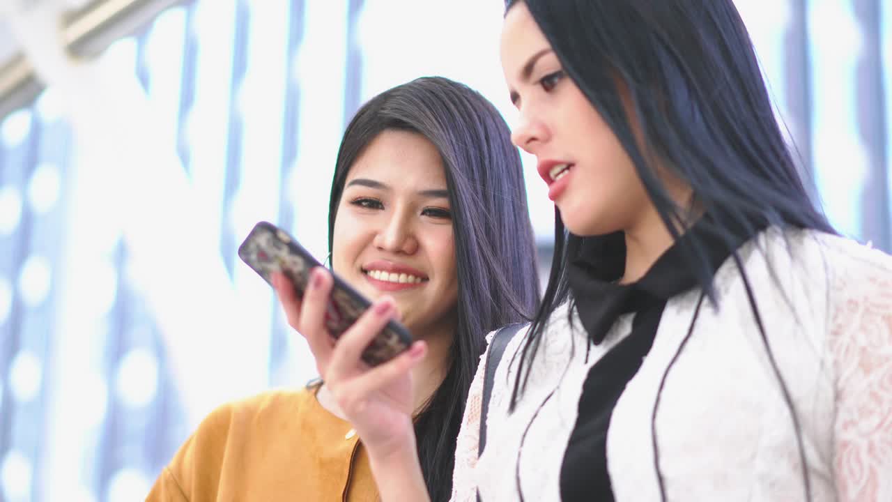 아름다운 아시아 여성은 스마트폰을 찾고 친구와 이야기합니다. 기술, 커뮤니케이션, 비즈니스, 온라인 쇼핑 및 패션의 개념.