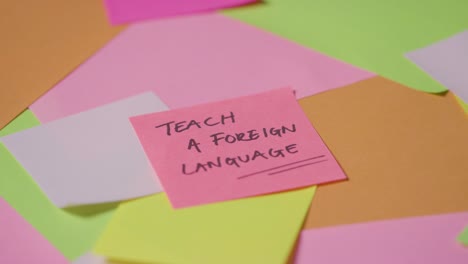 education concept of revolving sticky notes with teach a foreign language written on top note 1