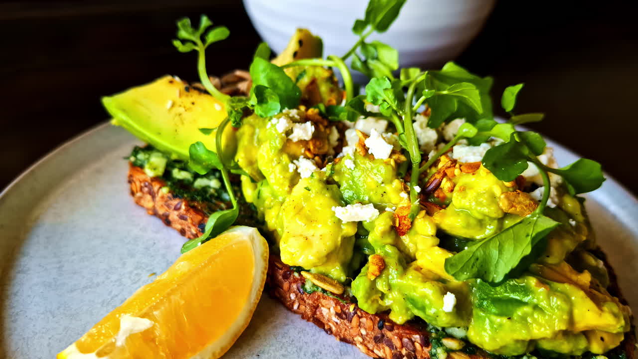 Fresh breakfast of avocado on bread, fruit salad, and a cold drink near Monkey Forest, Bali