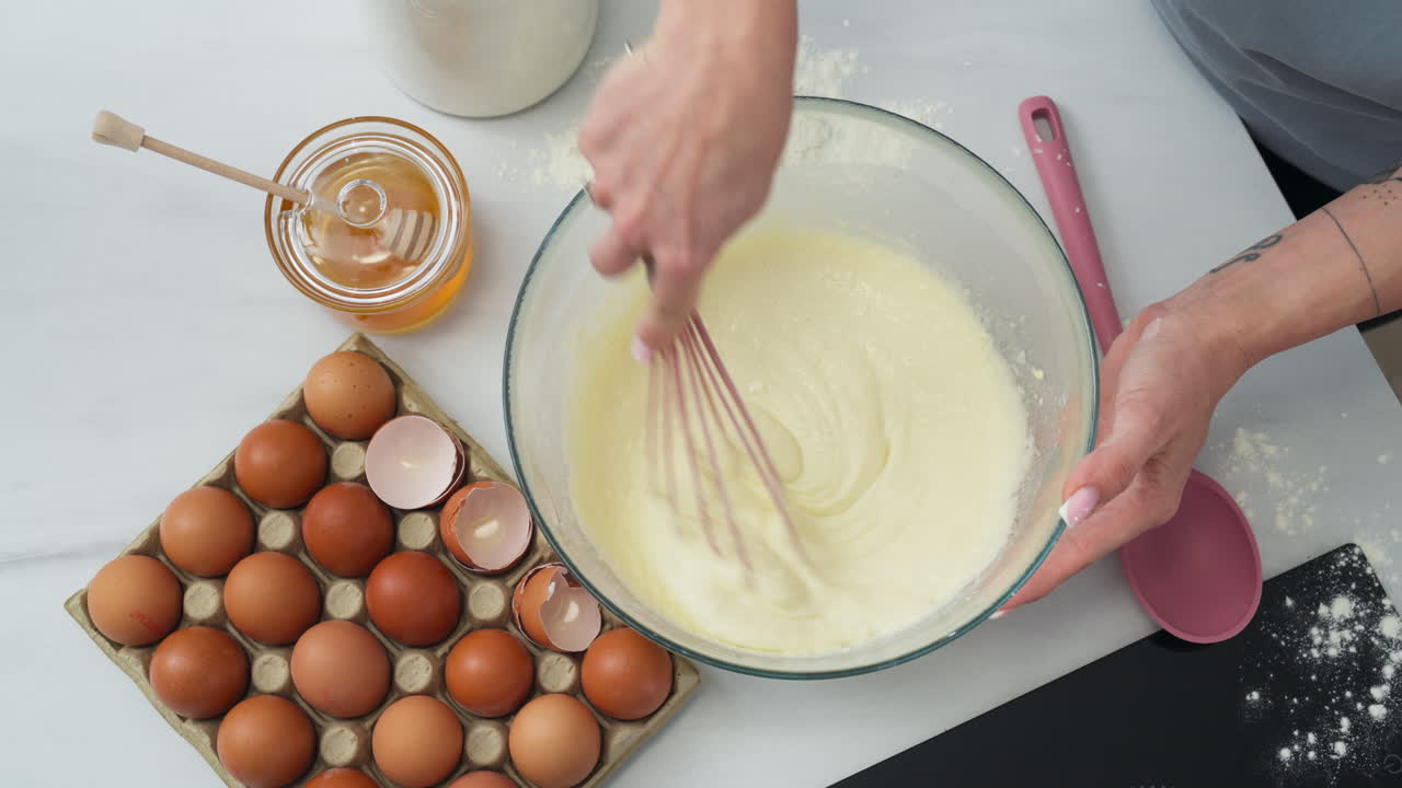 Person stirring a pastry dough in a bowl. Zenithal shot