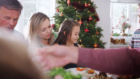 Familia-Multigeneracional-Sentada-A-La-Mesa-Disfrutando-Juntos-De-La-Comida-Navideña-En-Casa