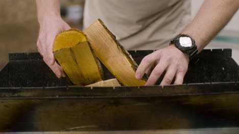 close-up van een blanke man die hout in een grill steekt op de camping in het bos