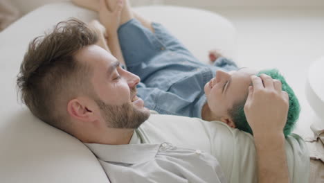 side view of young couple sitting on sofa, talking and caressing each other