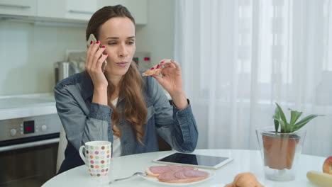 mujer hablando por teléfono mientras desayuna. chica comiendo un sándwich sabroso