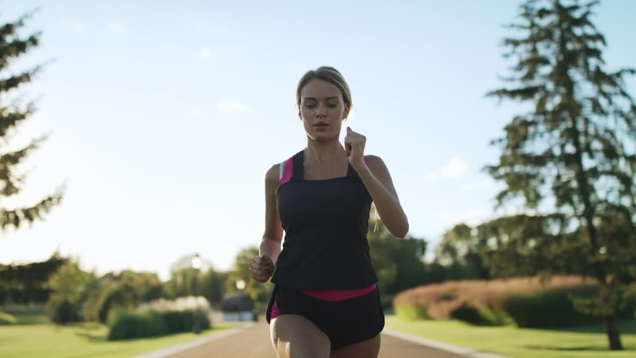 Athlete woman jogging in park. Female runner breathing hard at outdoor training