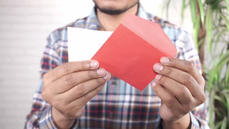 person holding a red envelope and a note