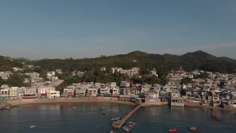 An-aerial-reverse-revealing-view-of-an-oceanfront-town-located-in-a-bay-surrounded-by-trees-and-nature