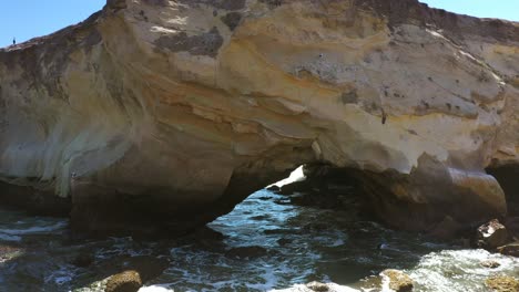 a stone arch in the ocean formed with erosion by waves along a picturesque shoreline - zoom out