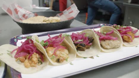 a handheld shot of a sampler platter of shrimp and fish tacos in a traditional sinaloan mexican restaurant kitchen