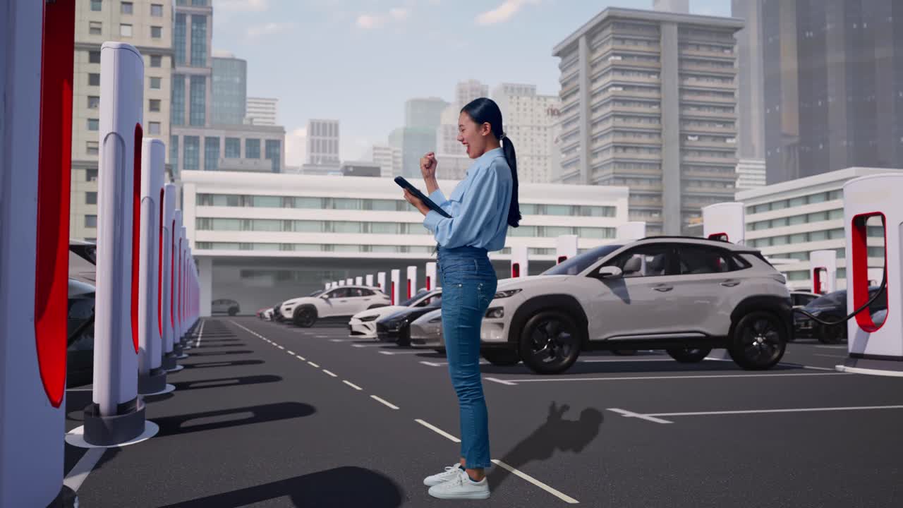 タブレットを持つアジア人女性の全身横顔。現代の都市ステーションで電気自動車が充電されており、彼女は拳を突き上げ歓声を上げている。